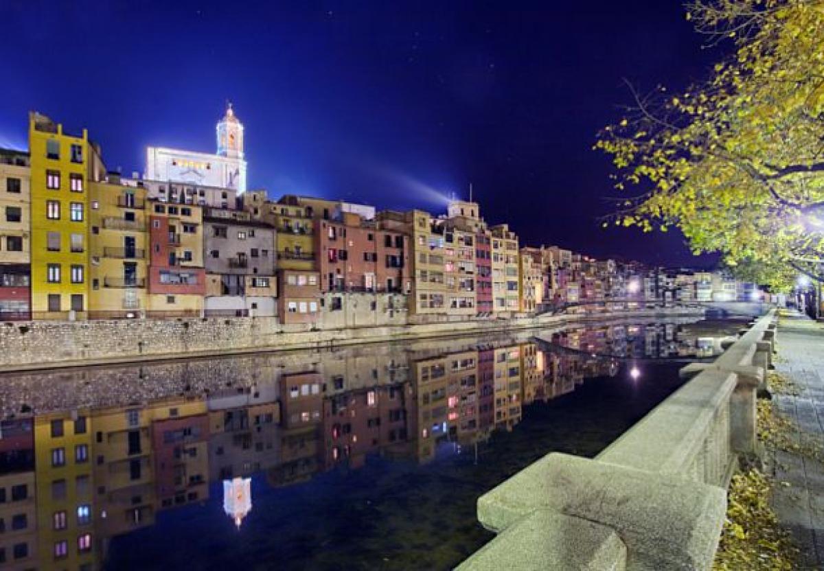 A night time shot of a river bank with stunning buildings in the background.