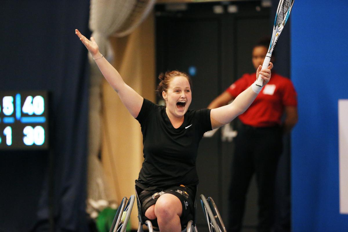 Women in wheelchair holding tennis racket, celebrating