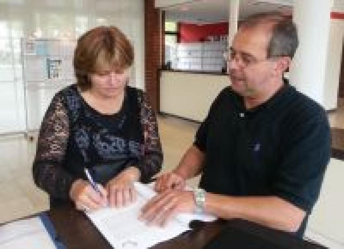 Man and woman sign a form standing on a table