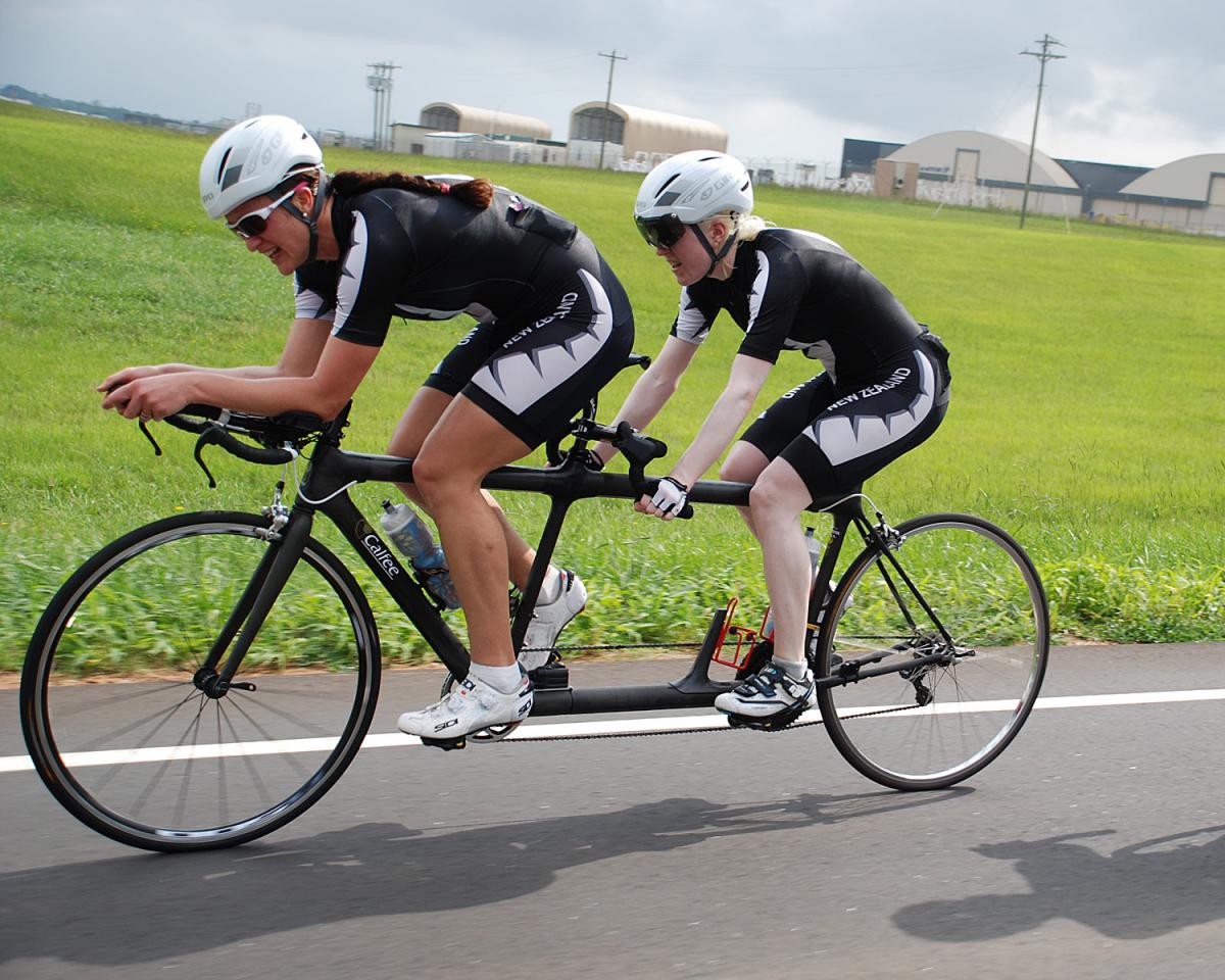 Two women cycle on a tandem