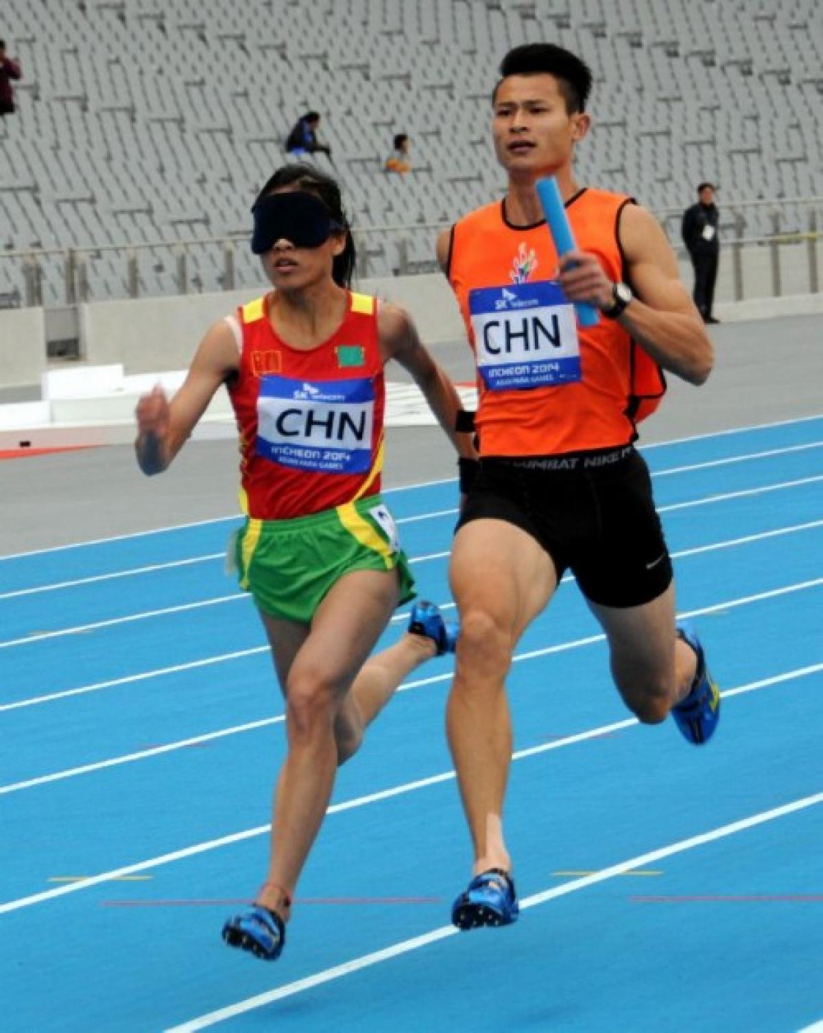 Blindfolded women with guide running in a relay