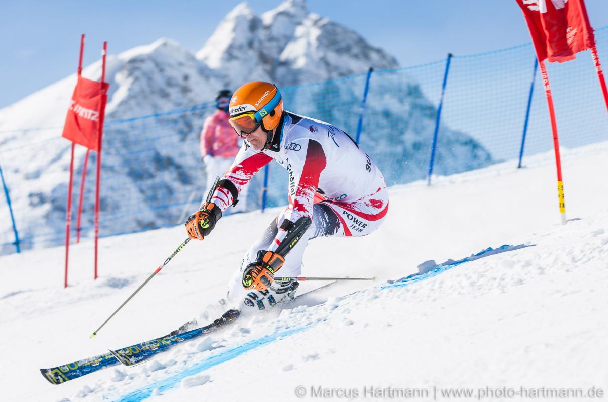 Matthias Lanzinger at 2015 World Cup Finals St. Moritz Man in race suit passing a gate on a ski slope