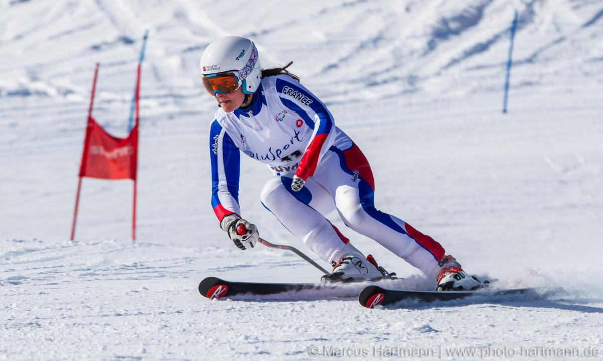 Female skier in racing suit passing a gate on a ski slope