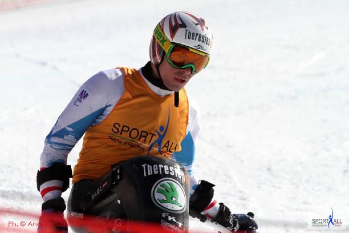 Men in sit ski looking focused, wearing helmet