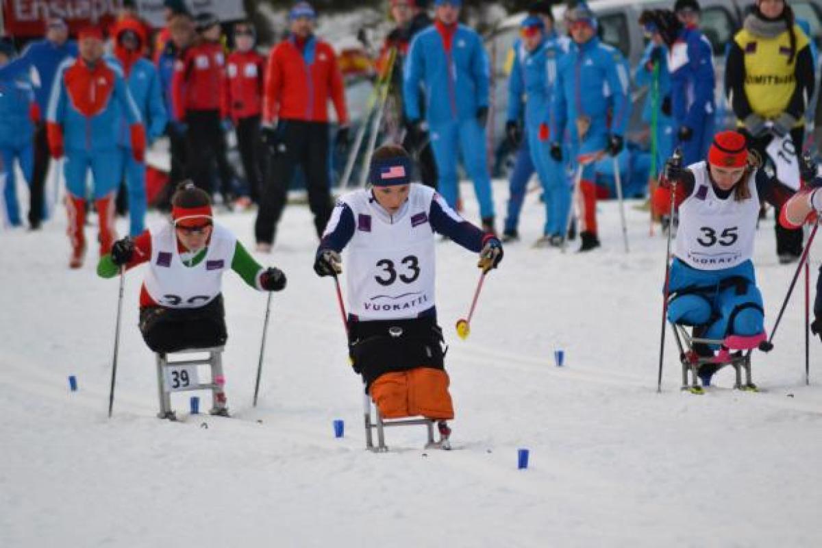 female athlete in a sit ski propelling herself forward