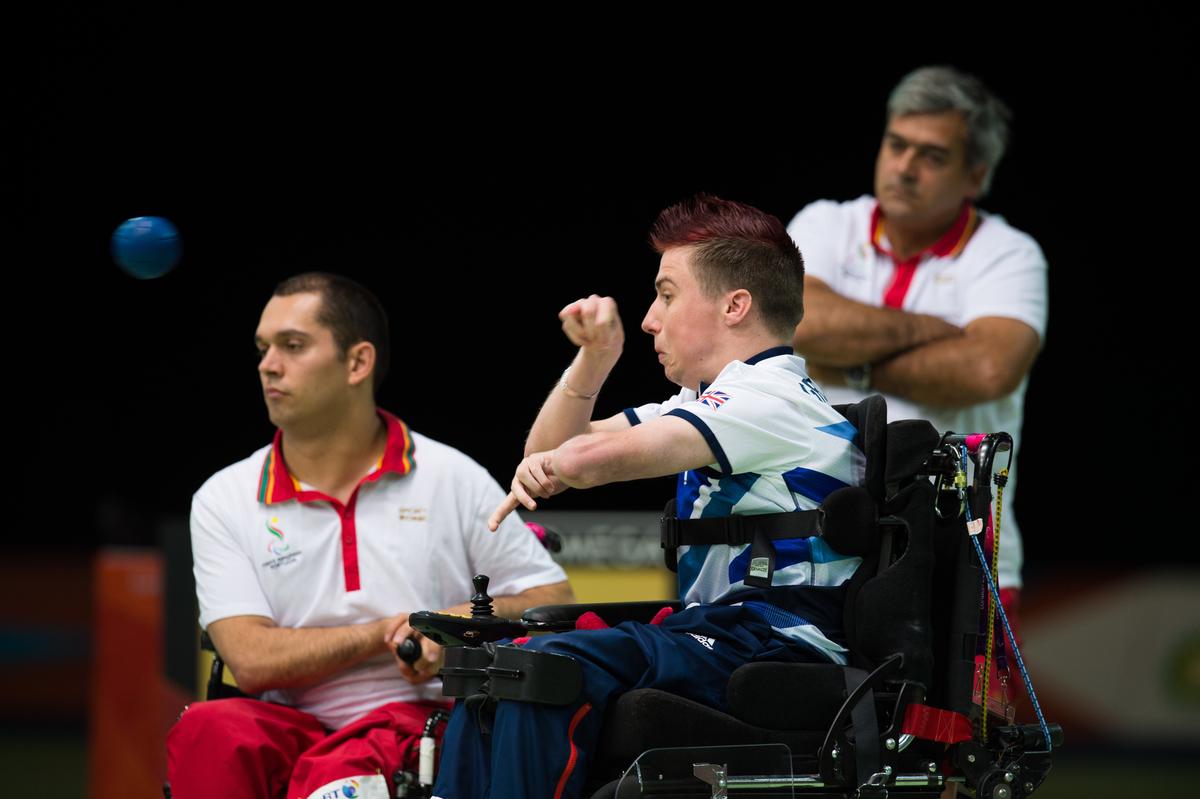 Two men in wheelchairs, one throwing a blue ball