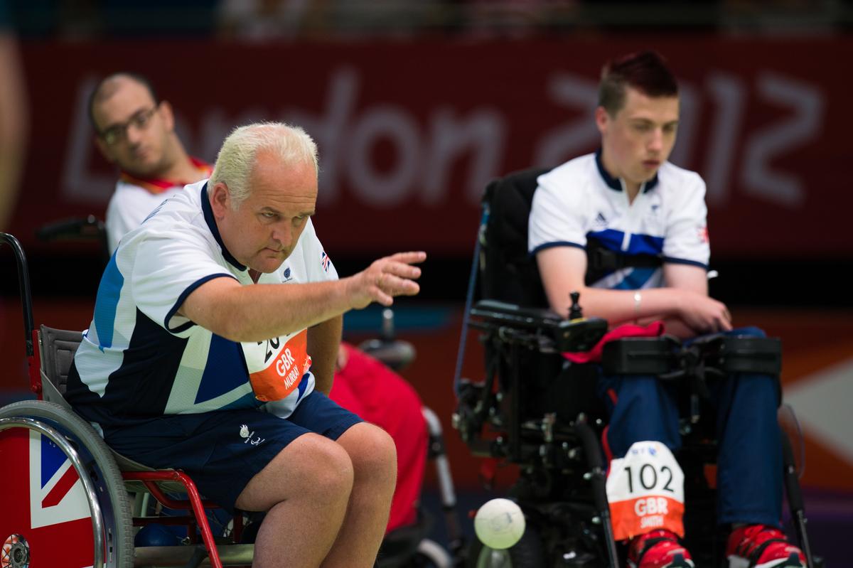 Two men in wheelchairs on a boccia field of play