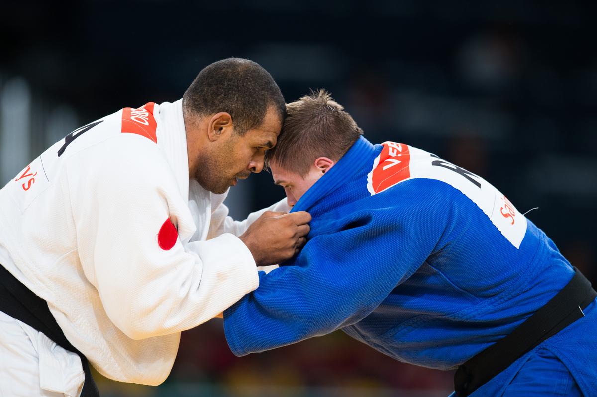 Antonio Tenorio and Vladimir Fedin hold on to each other with heads bowed close together, locked in battle