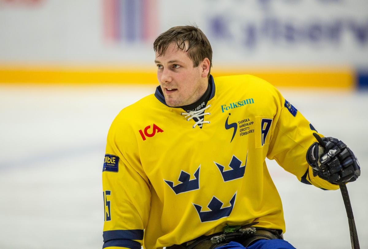 Swedish Para ice hockey player in his yellow Sweden jersey