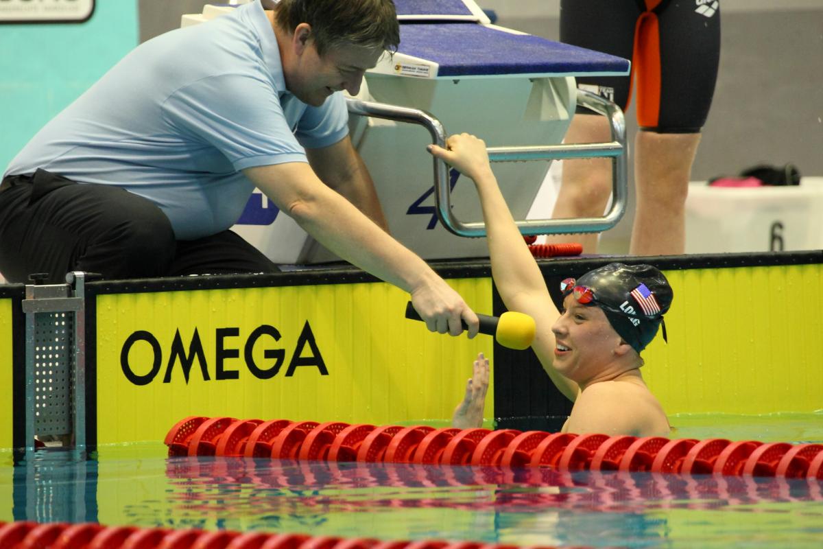 Women in pool giving an interview to someone at the pool edge