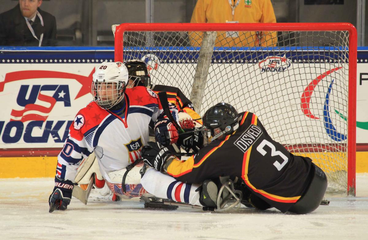 Two ice sledge hockey players fighting for the puck.