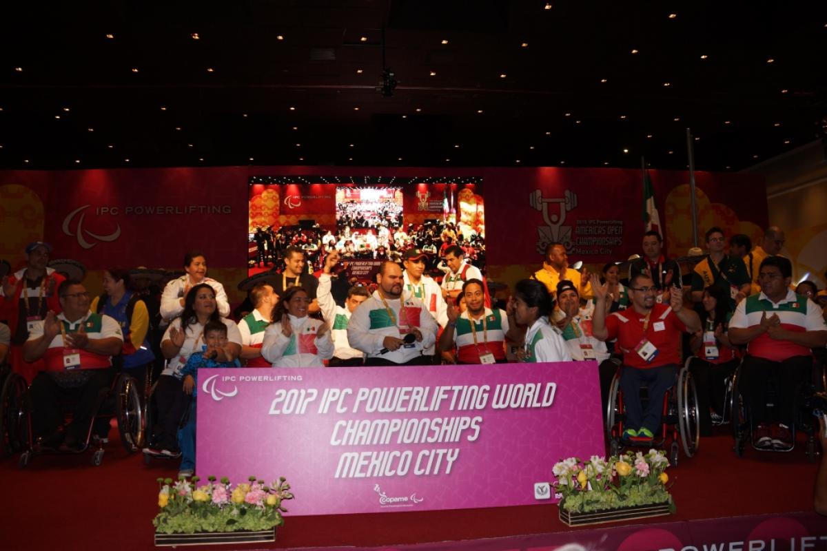 Group shot on a stage with a big sign in front