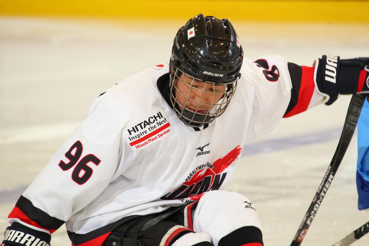 Masaharu Kumugai - 2015 IPC Ice Sledge Hockey World Championships Buffalo Man in white jersey and black helmet on a sledge