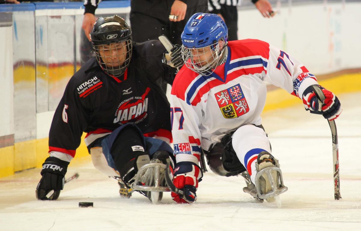 Two sledge hockey players fighting for the puk