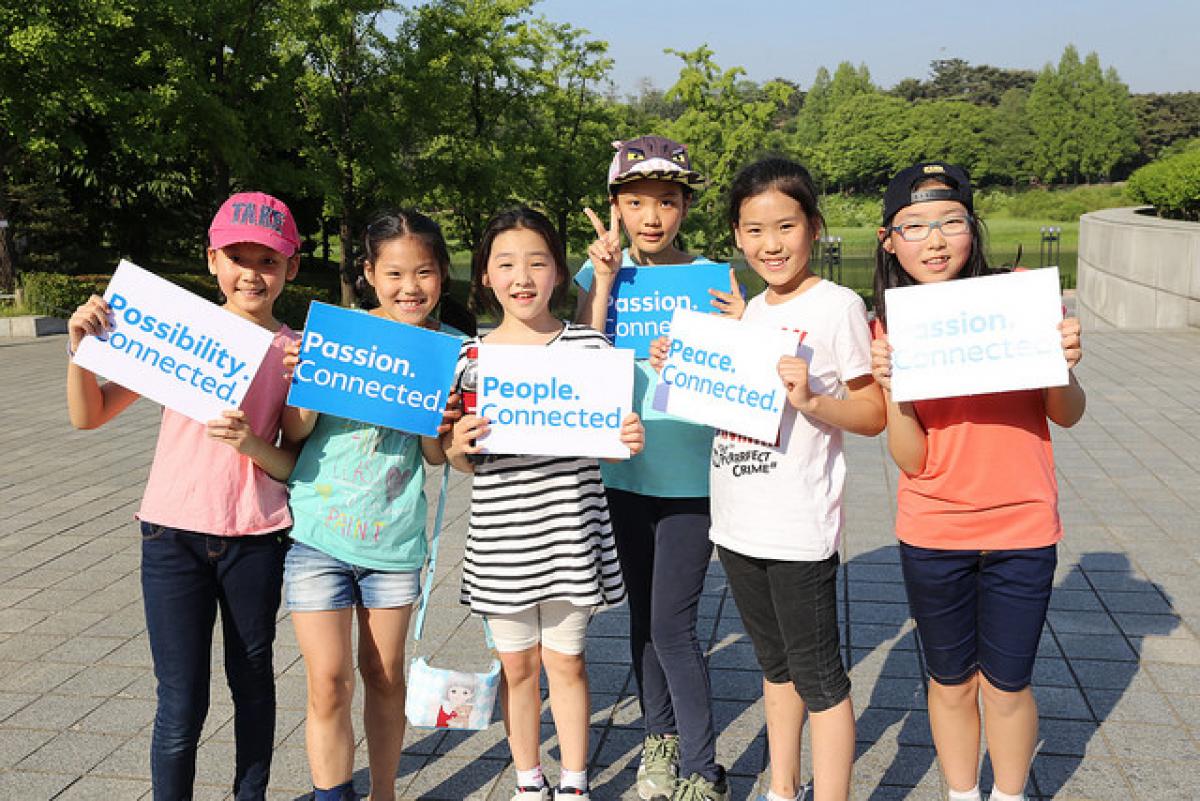 PyeongChang 2018 slogan: Passion. Connected. Group of kids showing signs with the words 'Passion. Connected'.