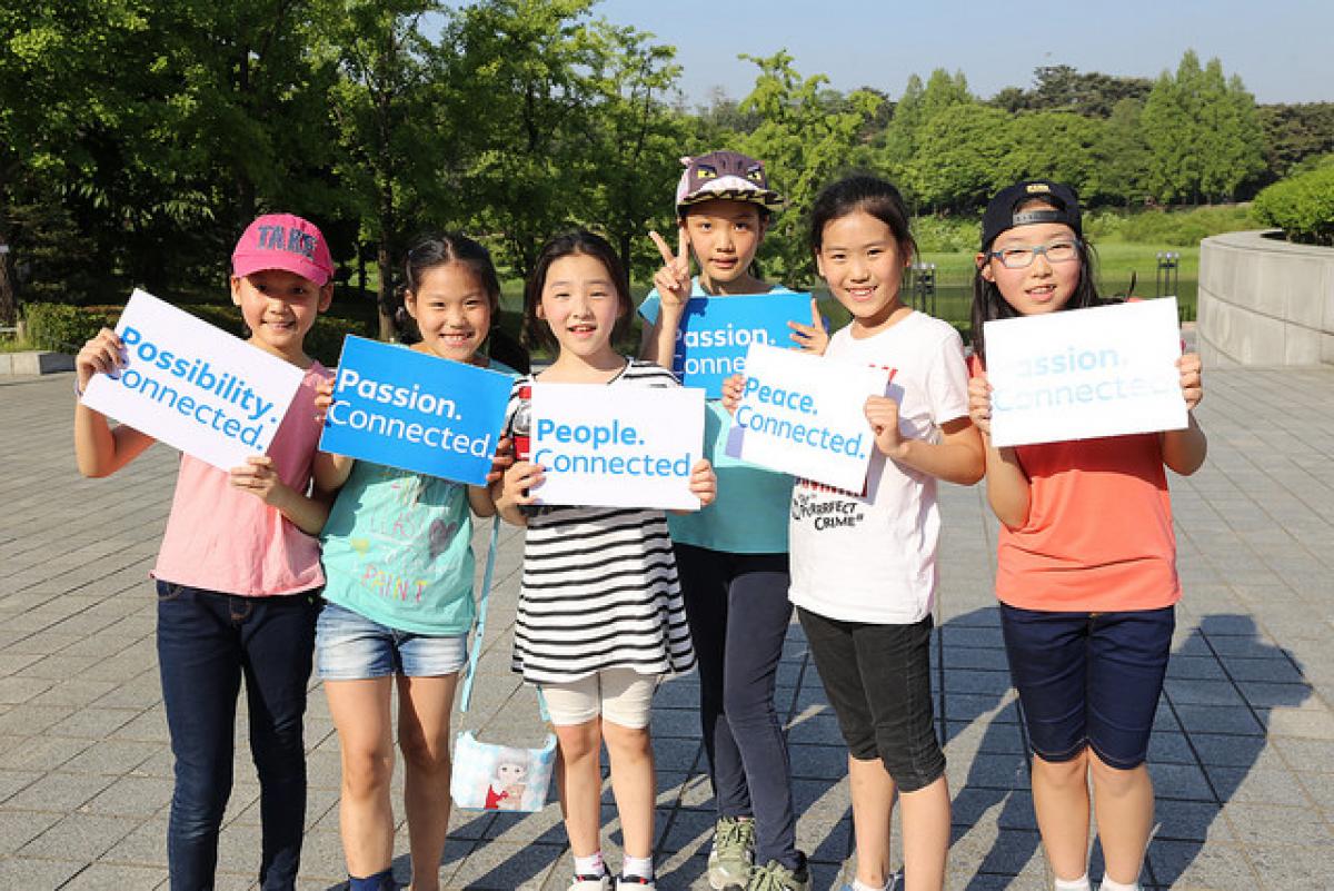 Group of kids showing signs with the words 'Passion. Connected'.