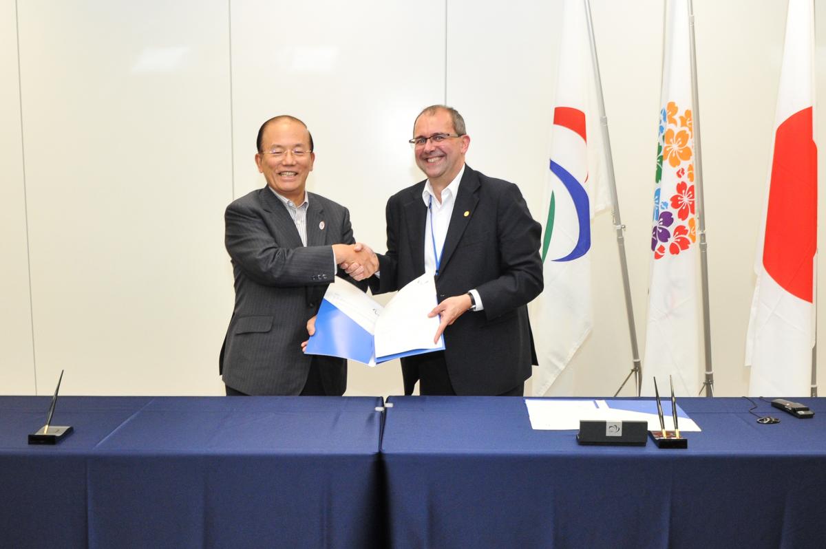 Two men shaking hands, smiling to the camera