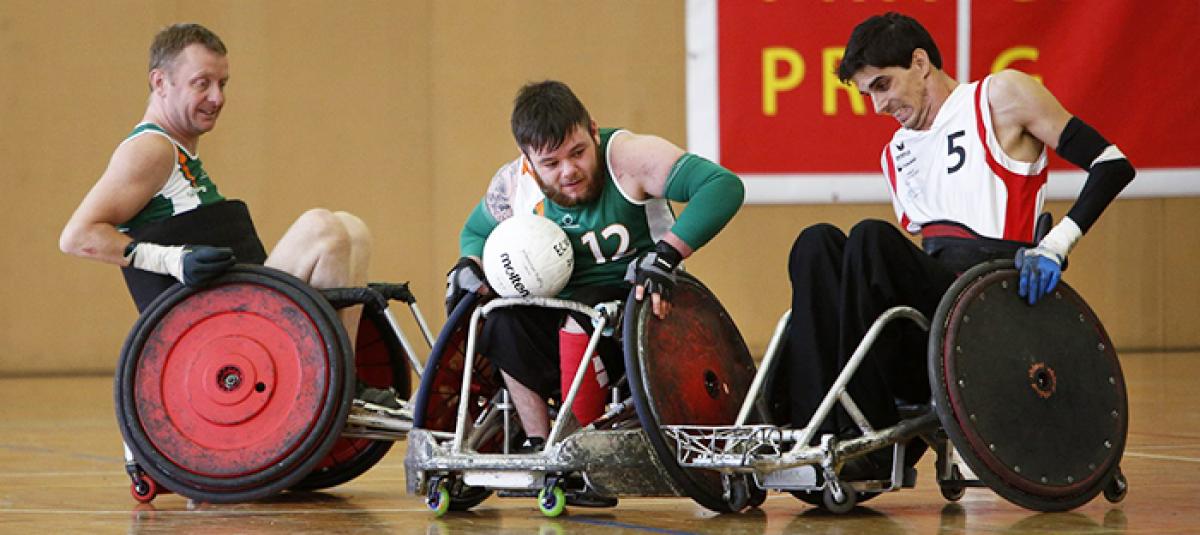 A group of male wheelchair rugby players battling for the ball