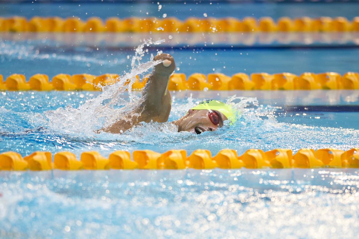 Swimmer with yellow cap doing freestyle.