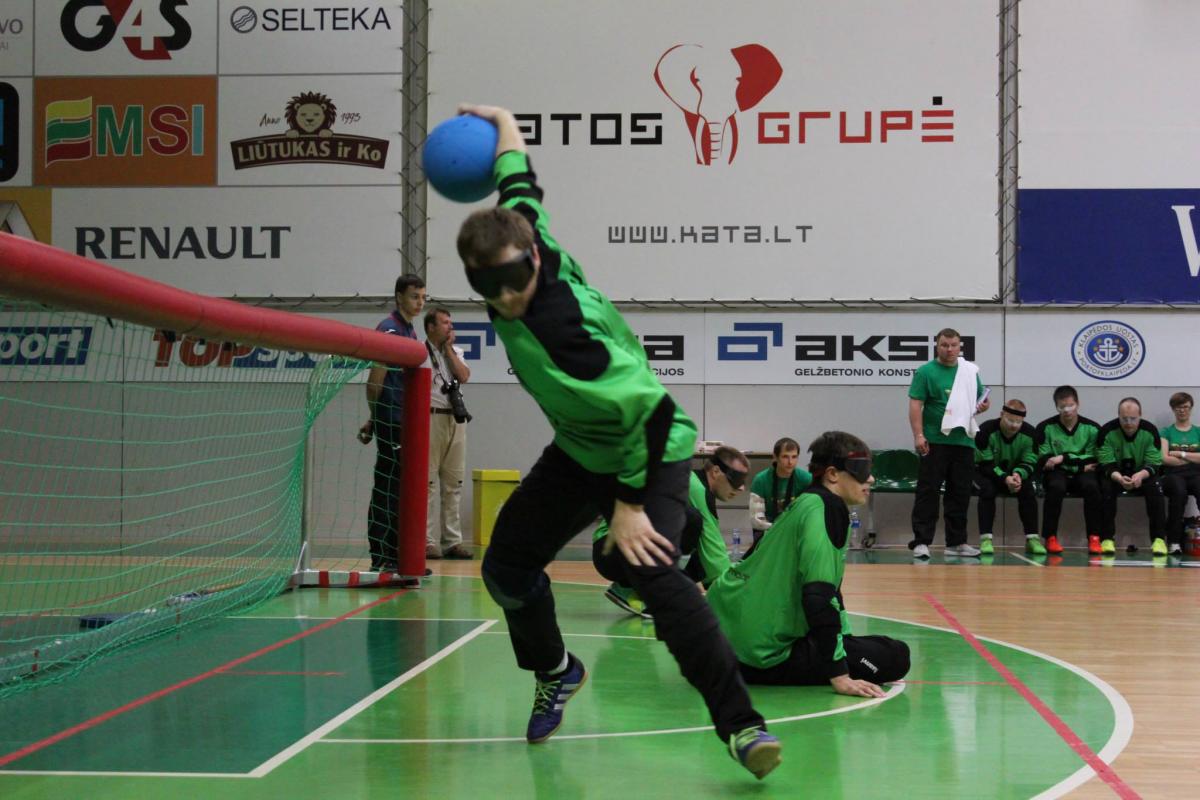 Blindfolded man on a field of play throwing a ball