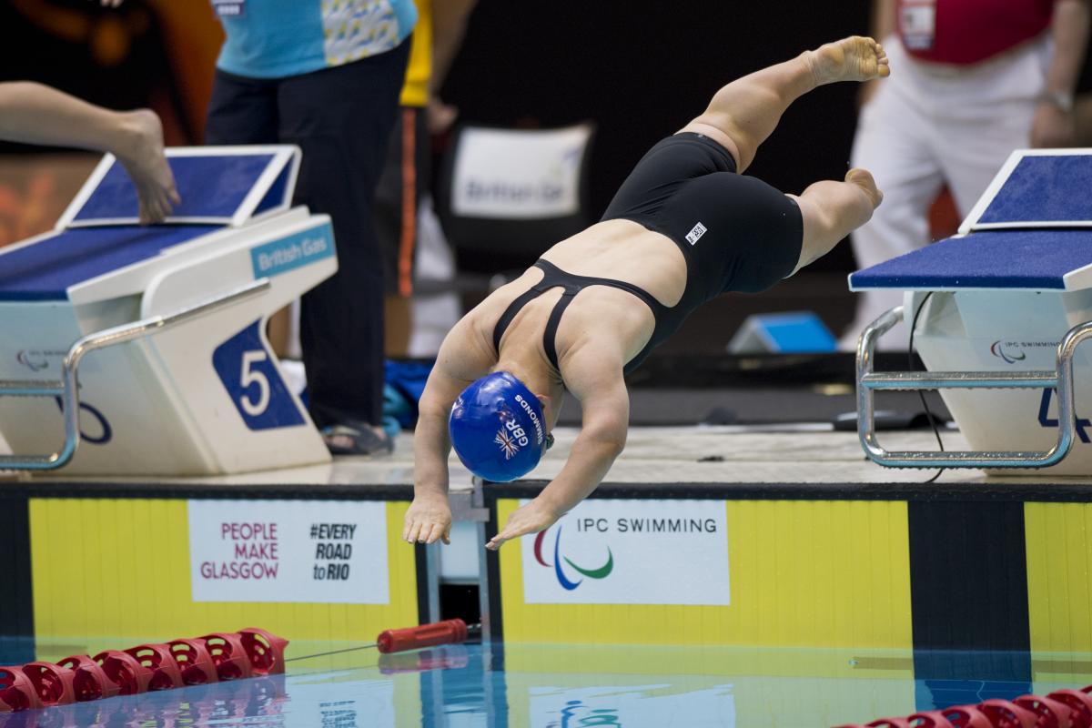 Swimmer with blue swim cap jumps off the start block.