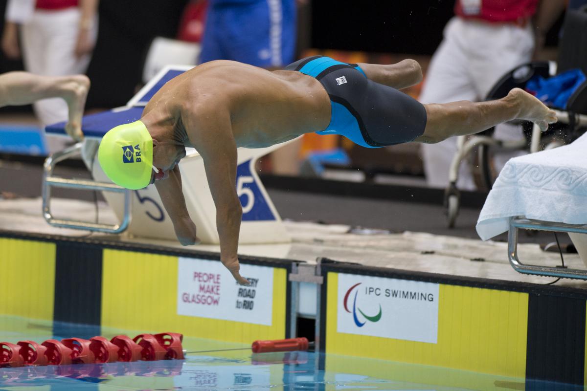 Swimmer with yellow swimp cap jumps of the blocks.