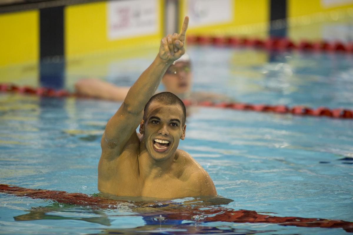 Andre Brasil - 2015 IPC Swimming World Championships Glasgow Man in water, holding one arm in the air, celebrating
