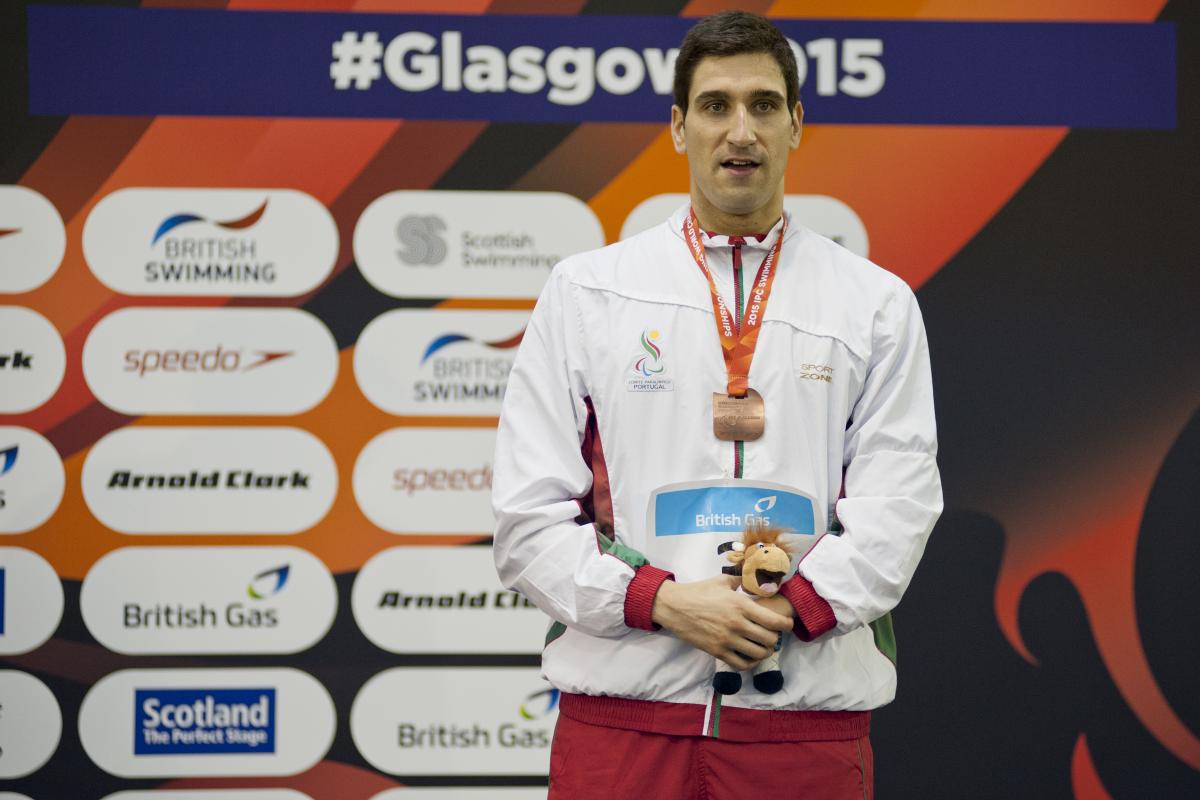 Man with medal around his neck standing on a podium