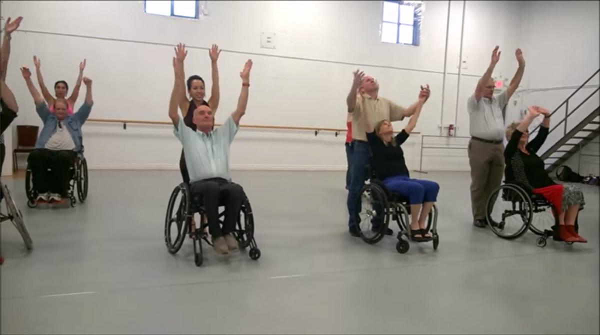 Group of people in wheelchairs and standing dancing