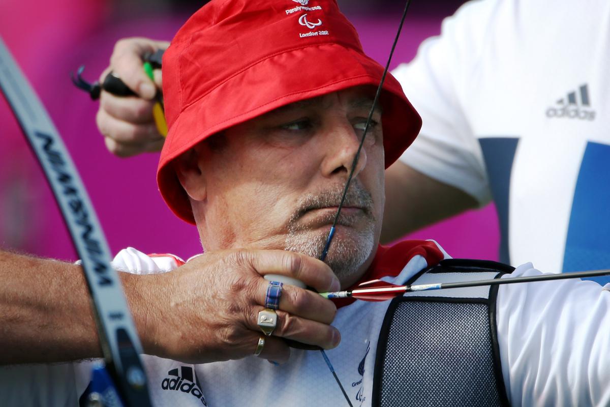 Close up of a man with a hat in an archery competition