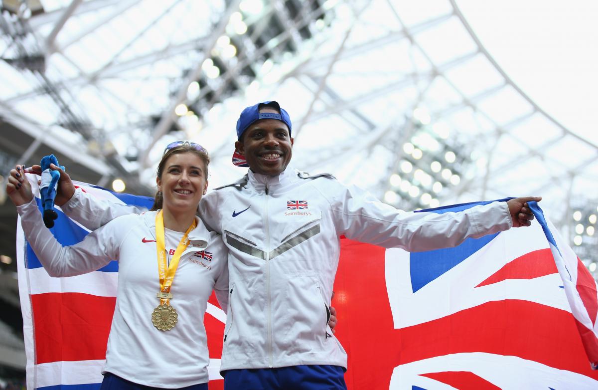 Man and woman on podium with a medal around her neck and a British flag