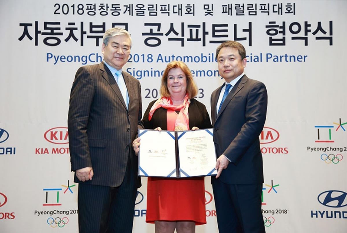 Three people smile to the camera, showing a piece of paper