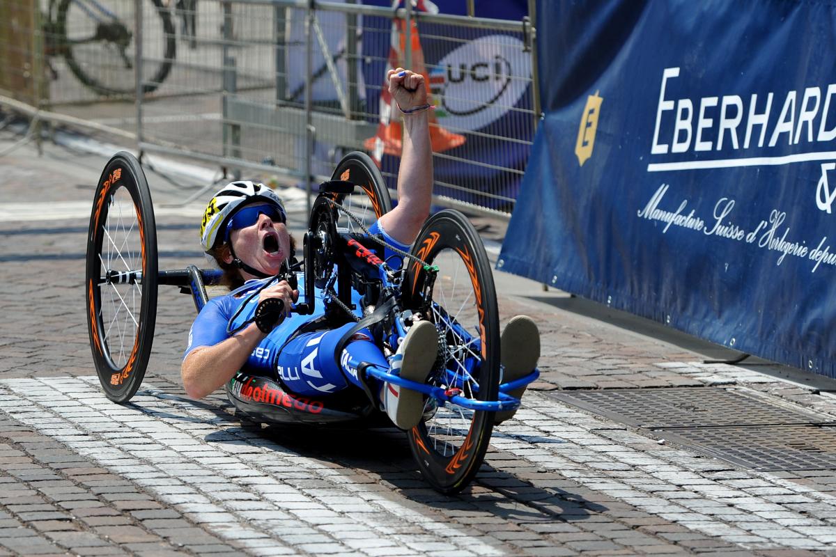 Woman on handbike crossing a finish line, celebrating