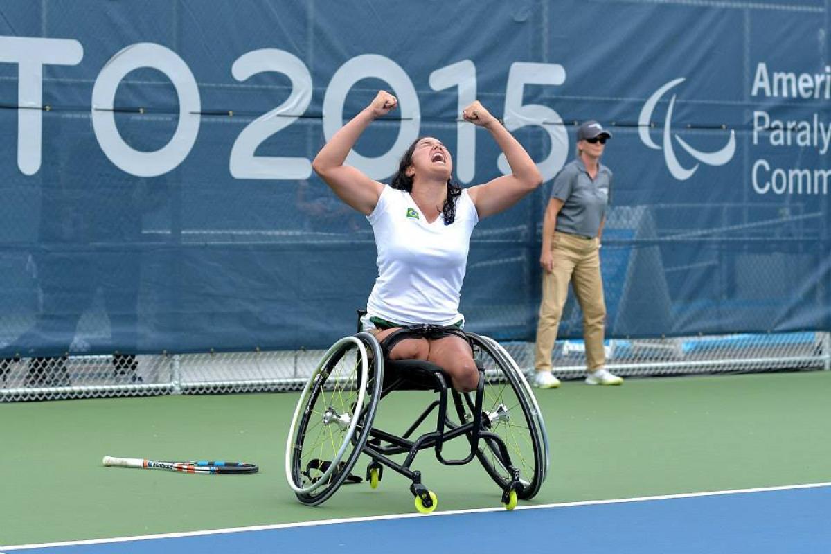 Natalia Mayara celebrating her victory with her hands in the air. She is looking at the sky, her mouth is open