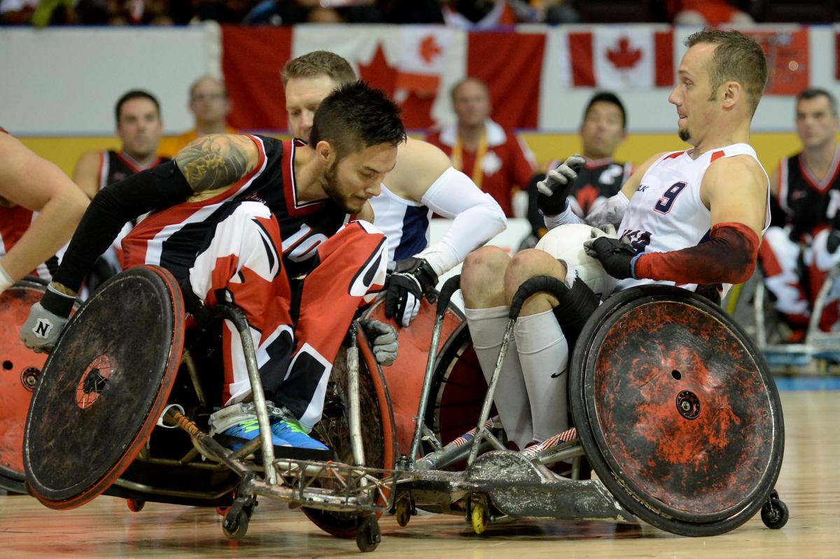 Two wheelchair rugby players tackeling each other