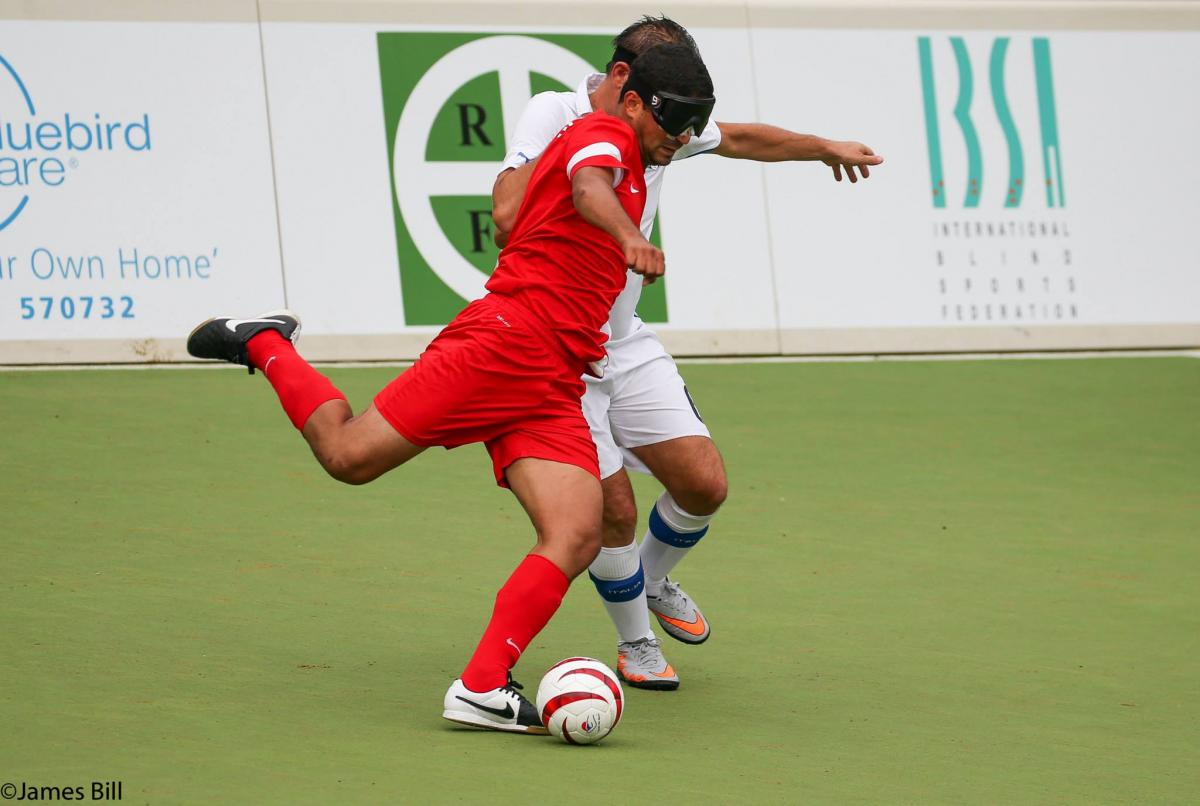 Two blindfolded football players fight for the ball