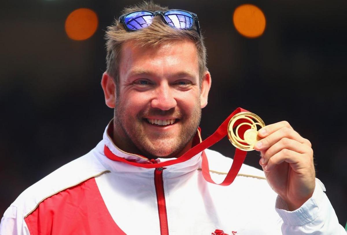 Gold medallist Dan Greaves of England poses on the podium during the medal ceremony for the Men's F42/44 Discus at Hampden Park during day five of the Glasgow 2014 Commonwealth Games 