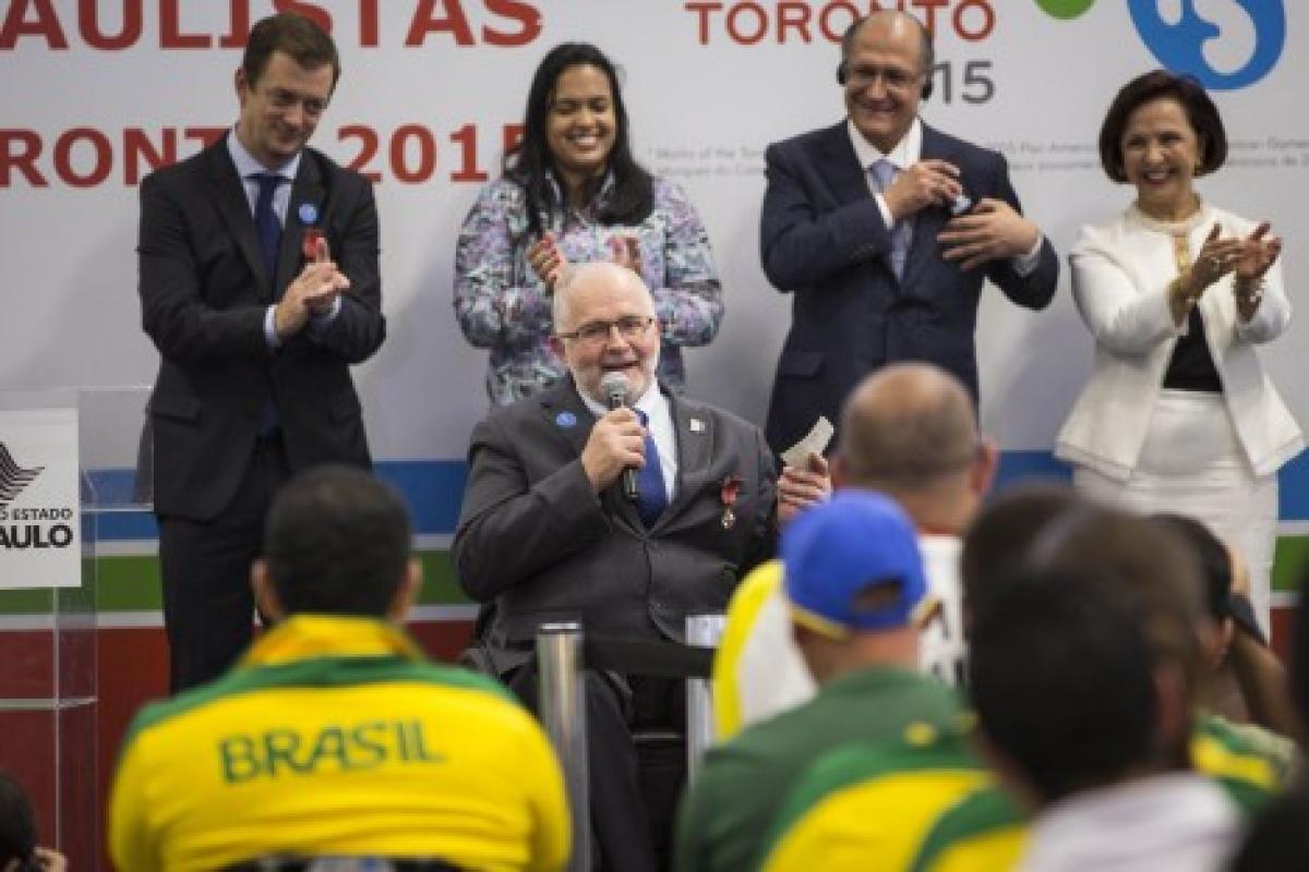 Man in wheelchair talking, people listening to him, applauding