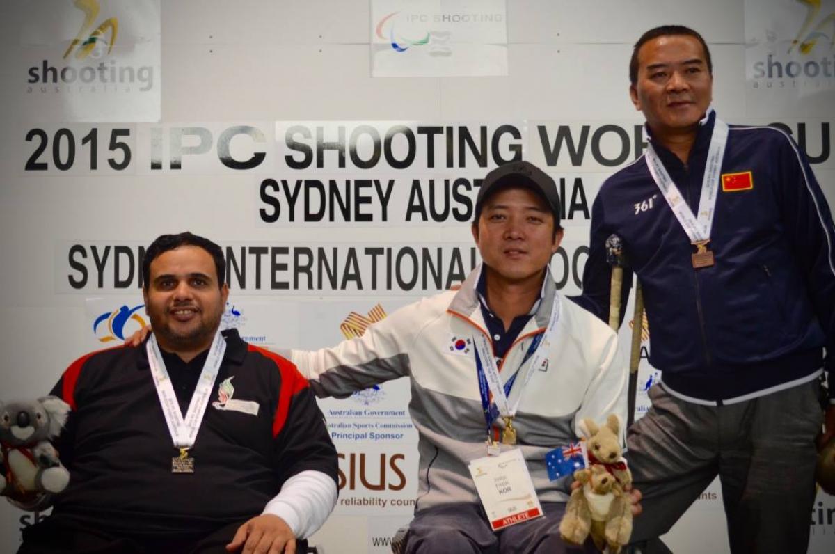 Three men on a podium with medals