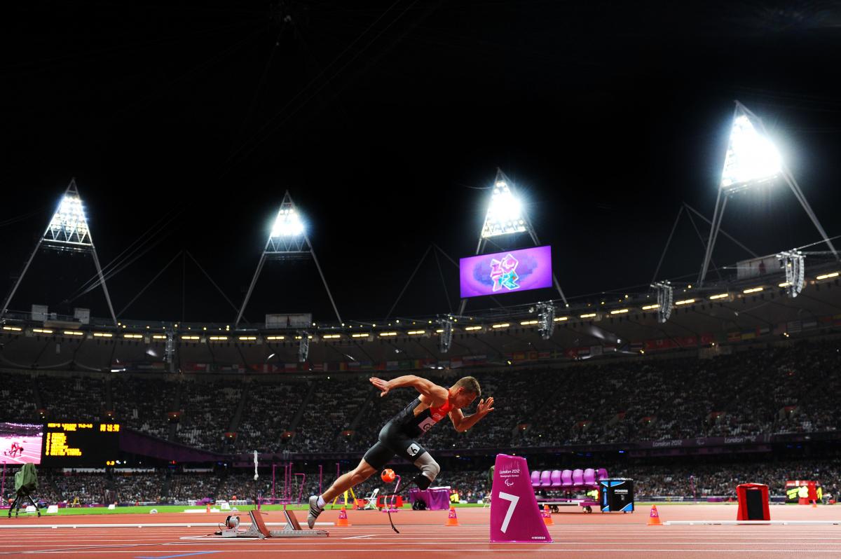 Man in a full stadium, starts sprinting from starting blocks