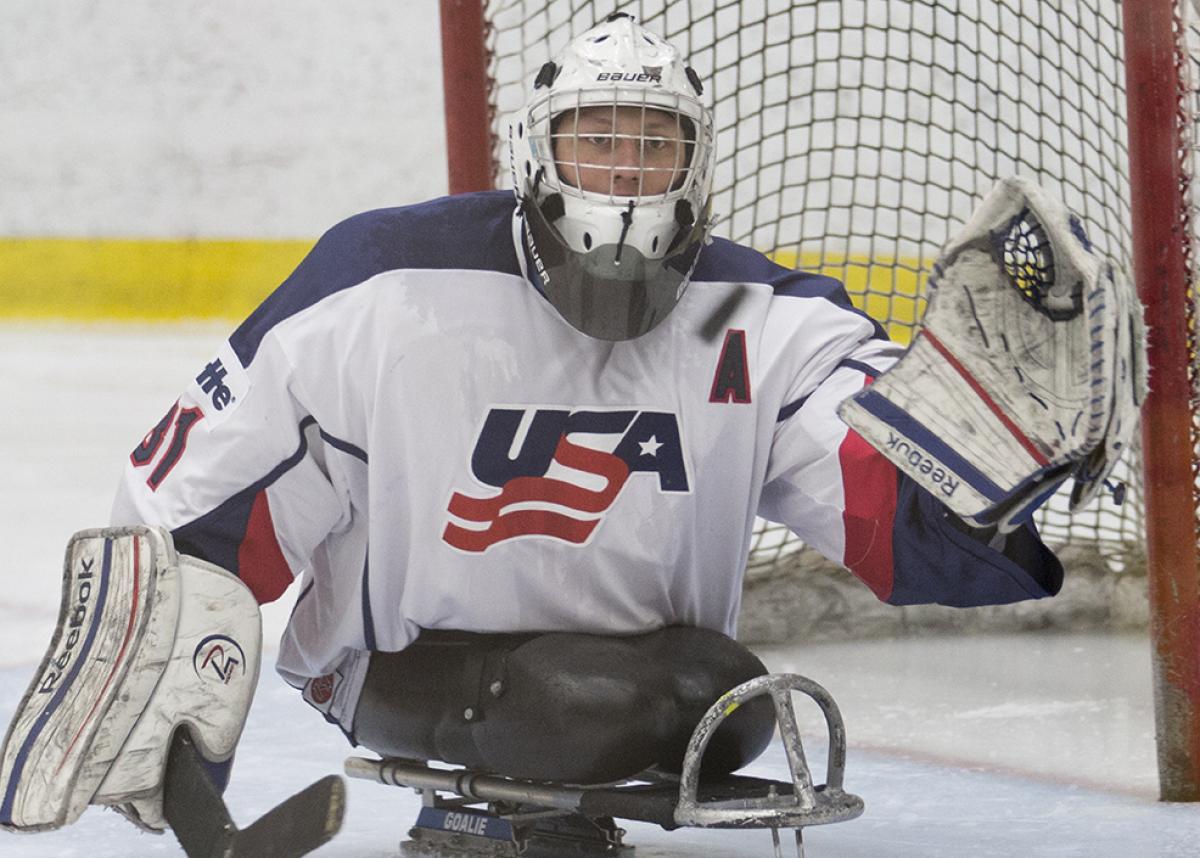 Man in ice sledge hockey uniform on a sledge on the ice