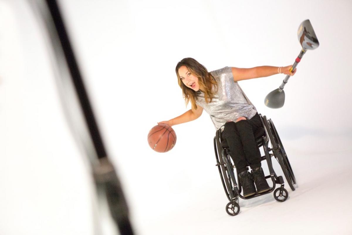 Woman in wheelchair with a basketball and a paddle in her hands