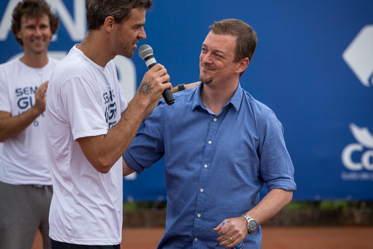 Two men on a stage, on speaking into a microphone
