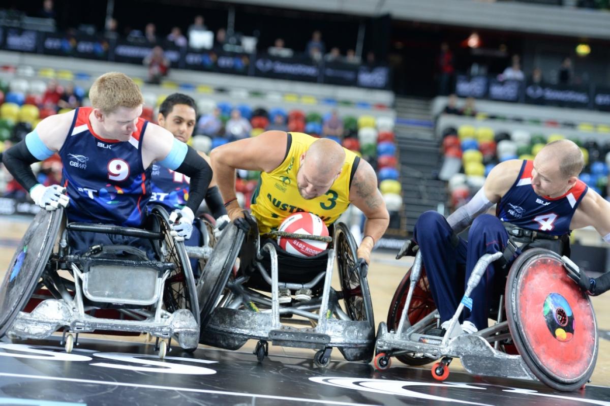 wheelchair rugby player in yellow jersey defending the ball