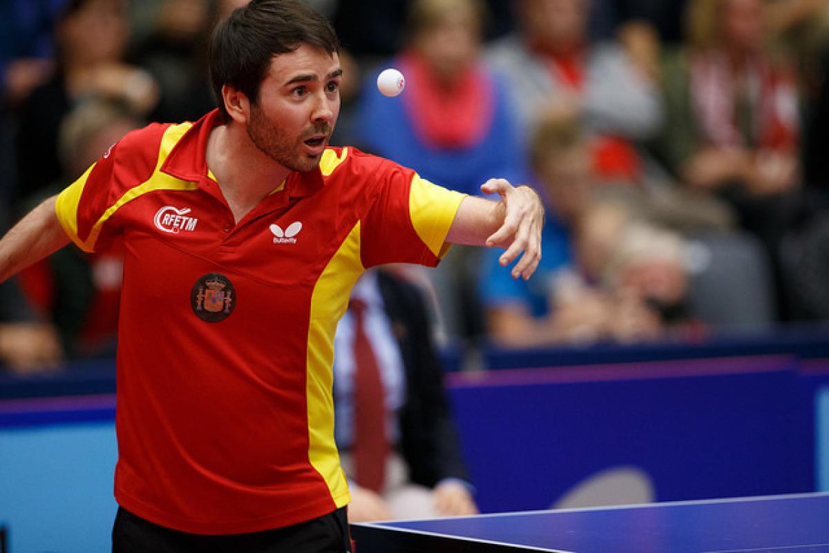 Man in red jersey focusing on a table tennis ball