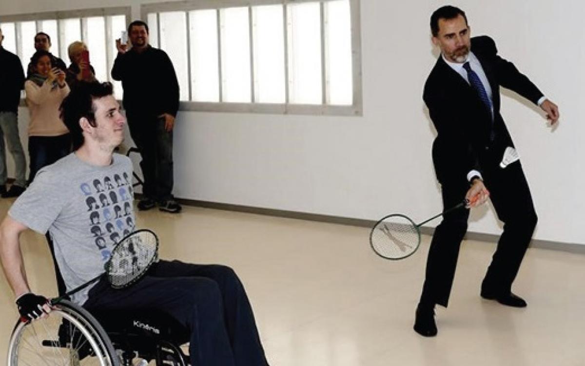 Two men, one standing, one in a wheelchair playing badminton