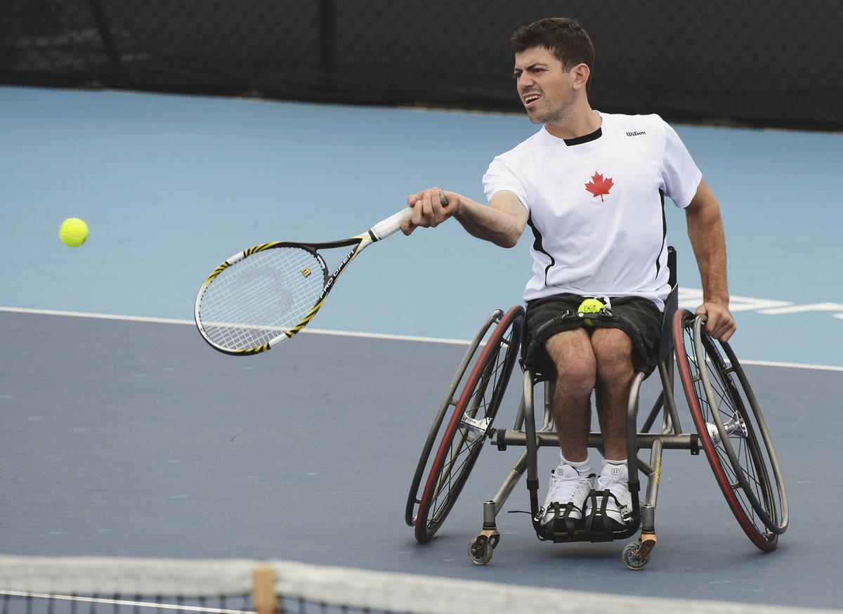Man in wheelchair returns a tennis ball
