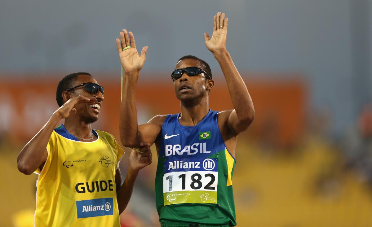 Blindfolded man and guide celebrate after crossing the finish line