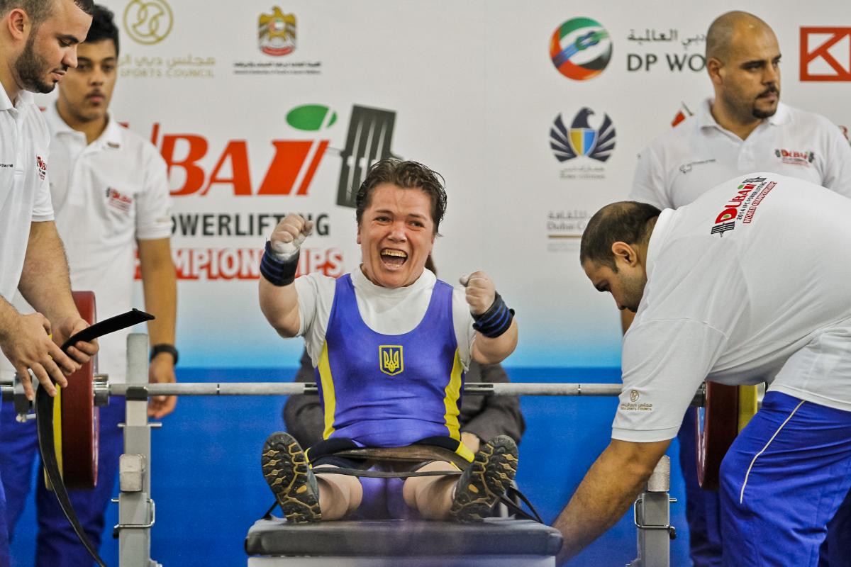 A powerlifter with short stature celebrates on the bench