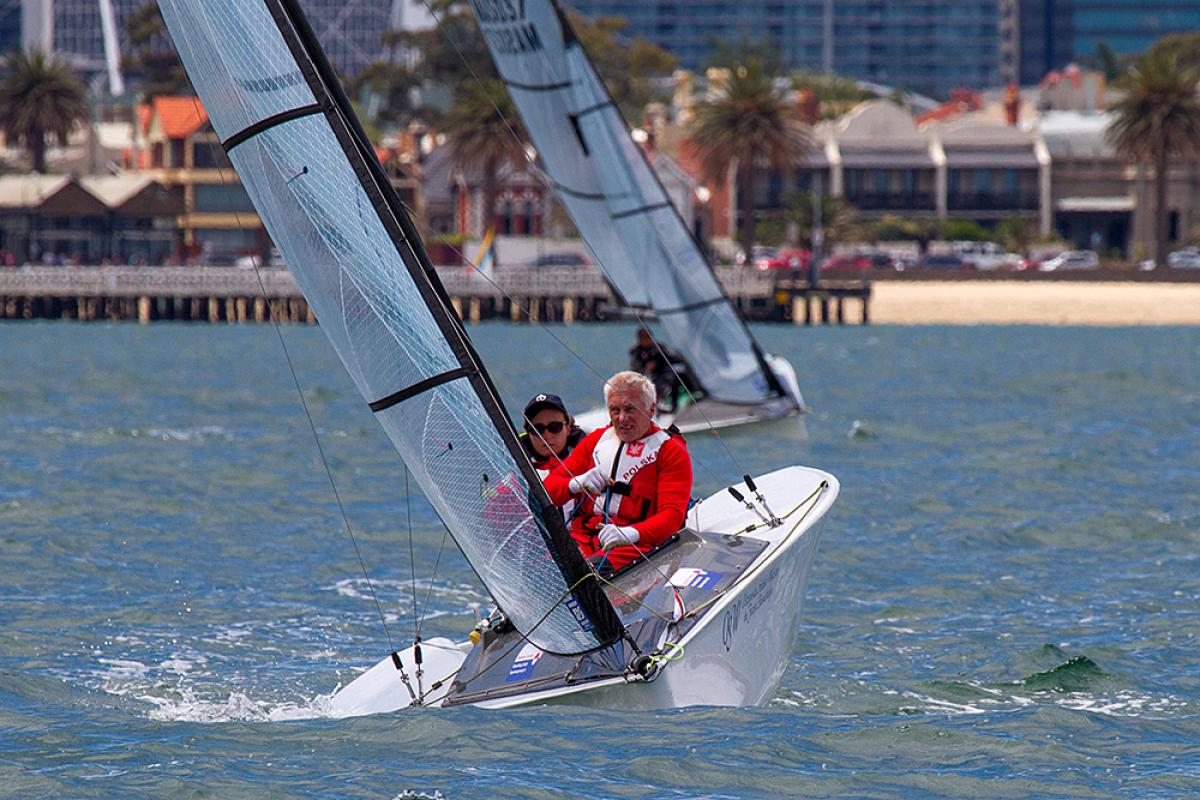 Two sailors in a boat on the water, wearinf red jackets